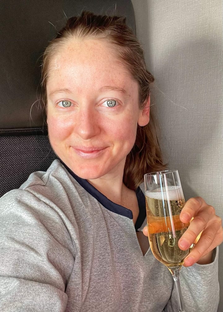 Clara Ritger in business class holding a glass of champagne.