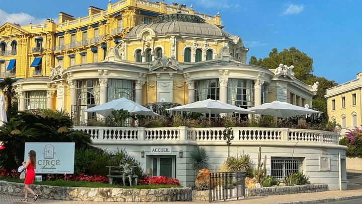 A gigantic resort in Belle Epoque architecture style, painted sunflower yellow with cream columns.