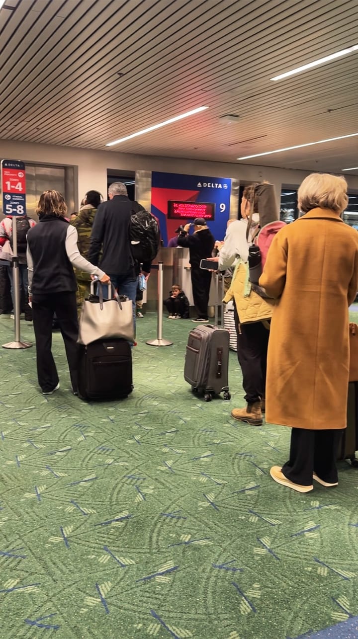 Passengers wait in line with carry-on bags to board a