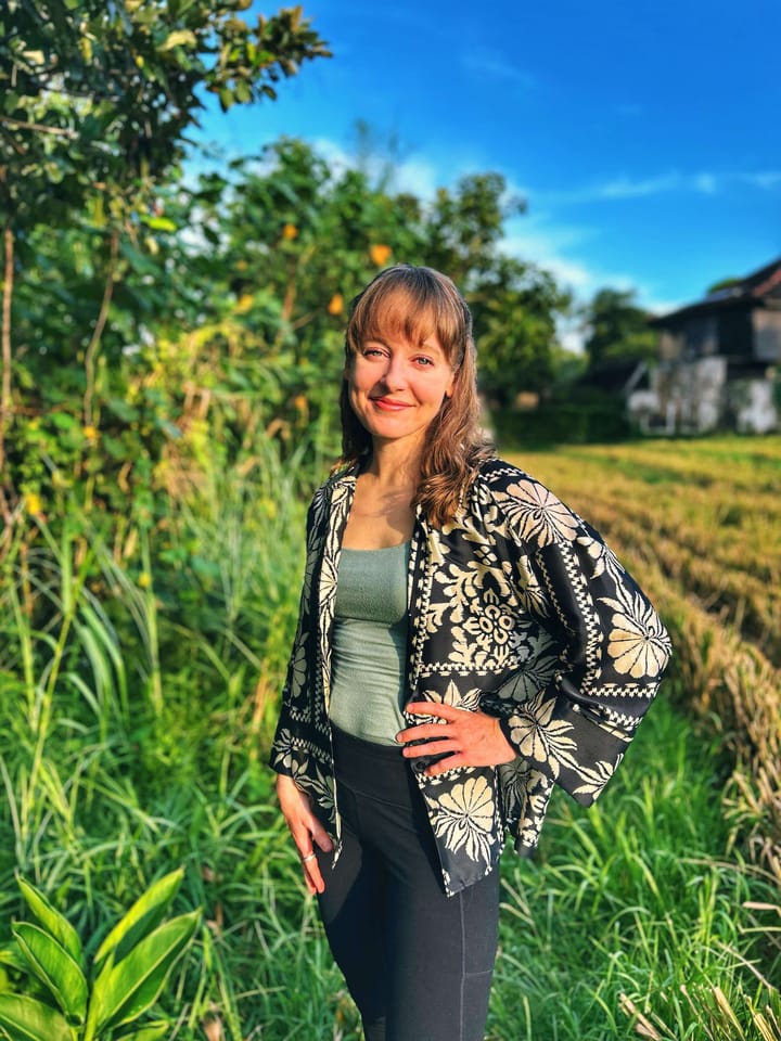 Clara Ritger stands in a rice field smiling with her hand on her hip. 